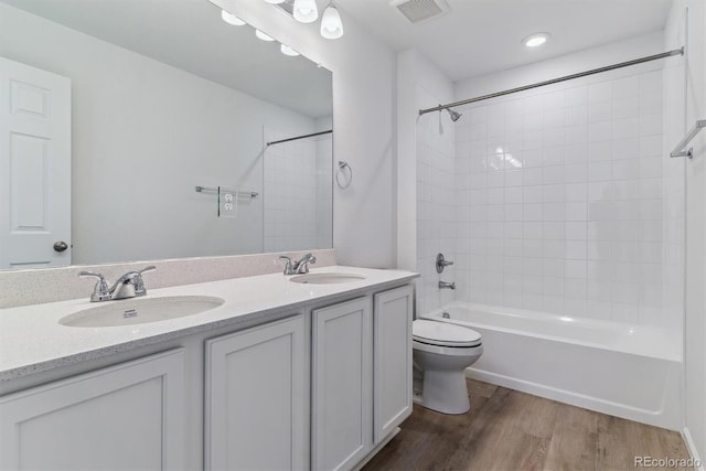 full bathroom featuring hardwood / wood-style flooring, vanity, toilet, and tiled shower / bath combo