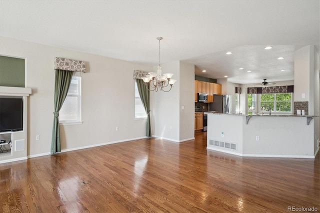 unfurnished living room with a chandelier, recessed lighting, wood finished floors, a ceiling fan, and baseboards
