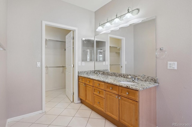 full bathroom featuring tile patterned flooring, double vanity, a walk in closet, and baseboards