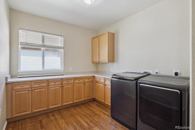 laundry room featuring washer and dryer, cabinet space, and wood finished floors