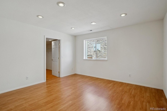 unfurnished room featuring light wood finished floors, baseboards, and recessed lighting