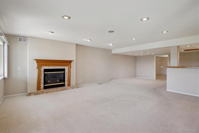 unfurnished living room with light colored carpet, a premium fireplace, baseboards, and recessed lighting