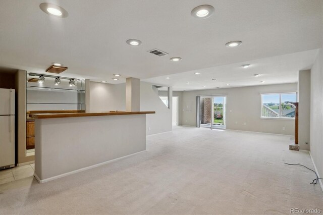 unfurnished living room featuring recessed lighting, light carpet, baseboards, and bar