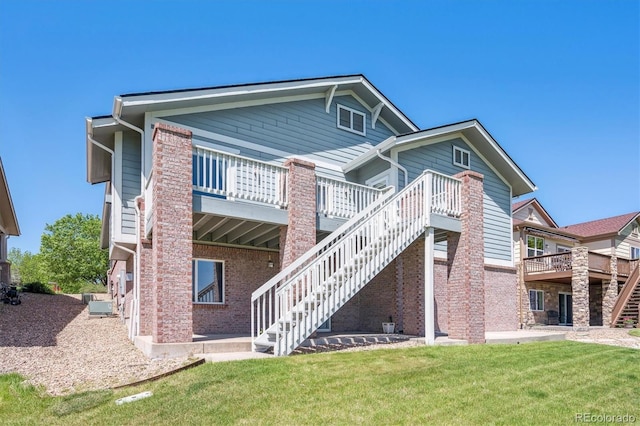rear view of house featuring stairs, a yard, a deck, and brick siding