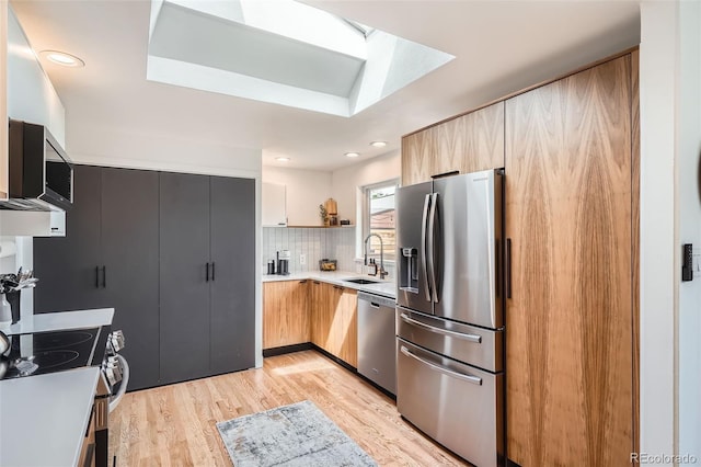 7491 W 45th Ave, Wheat Ridge, CO 80033 - kitchen with appliances with stainless steel finishes, a sink, light wood-style flooring, light countertops, and a skylight