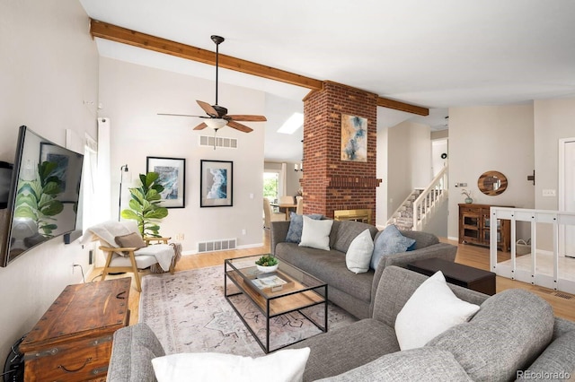 living room featuring lofted ceiling with beams, stairway, wood finished floors, and visible vents