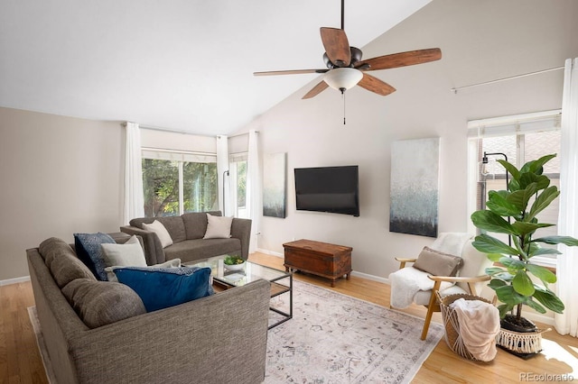 living area featuring light wood-style floors, a healthy amount of sunlight, baseboards, and a ceiling fan