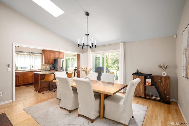 dining room with a chandelier, light wood-style flooring, and baseboards