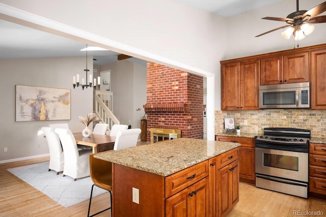 kitchen featuring hanging light fixtures, appliances with stainless steel finishes, brown cabinets, and a center island