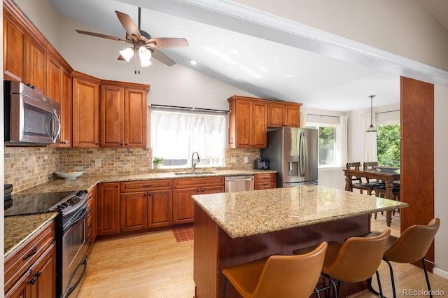 kitchen with stainless steel appliances, pendant lighting, brown cabinets, and a sink