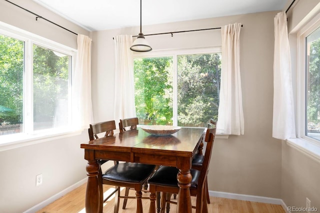 dining space with light wood-type flooring and baseboards