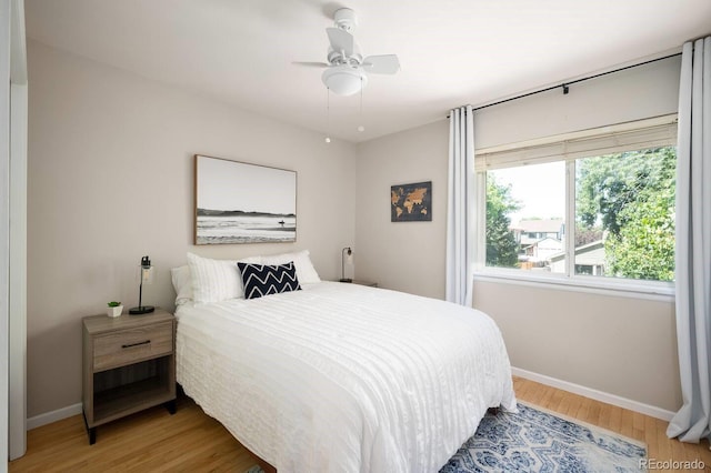 bedroom with ceiling fan, wood finished floors, and baseboards