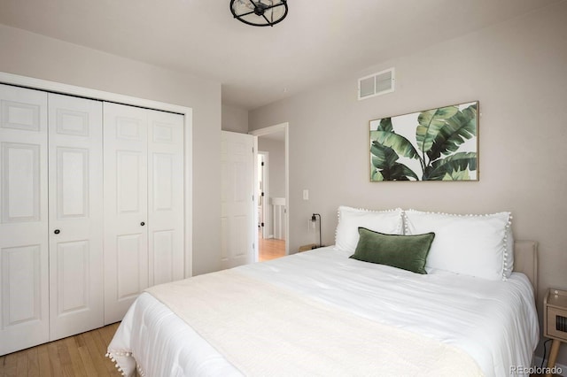 bedroom featuring a closet, visible vents, and light wood finished floors