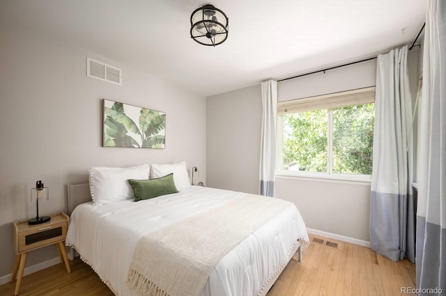 bedroom featuring light wood-style floors, visible vents, and baseboards