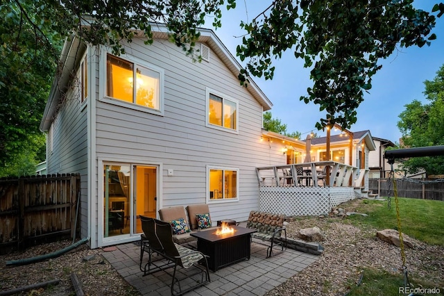 back of property with an outdoor fire pit, fence, a deck, and a patio