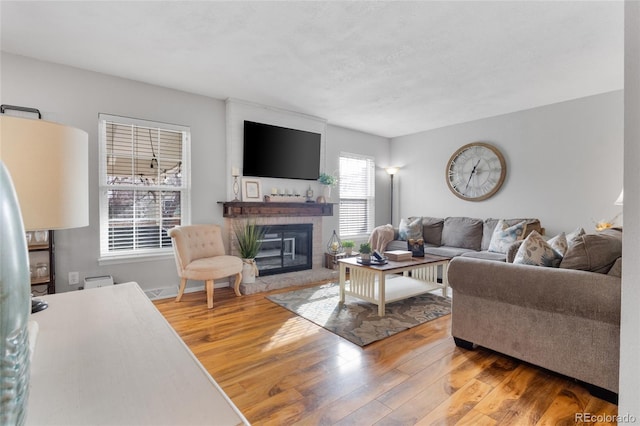 living area featuring a brick fireplace and wood finished floors