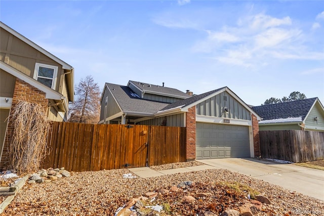 view of front of home with concrete driveway, an attached garage, fence, board and batten siding, and brick siding