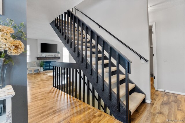 staircase featuring wood finished floors and baseboards