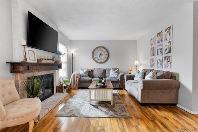 living area with a brick fireplace, baseboards, and wood finished floors