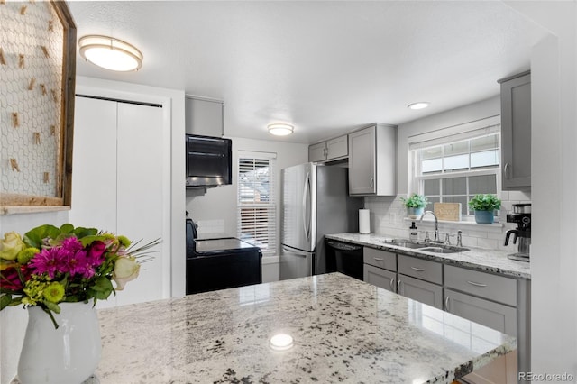 kitchen with black appliances, light stone counters, gray cabinets, and a sink