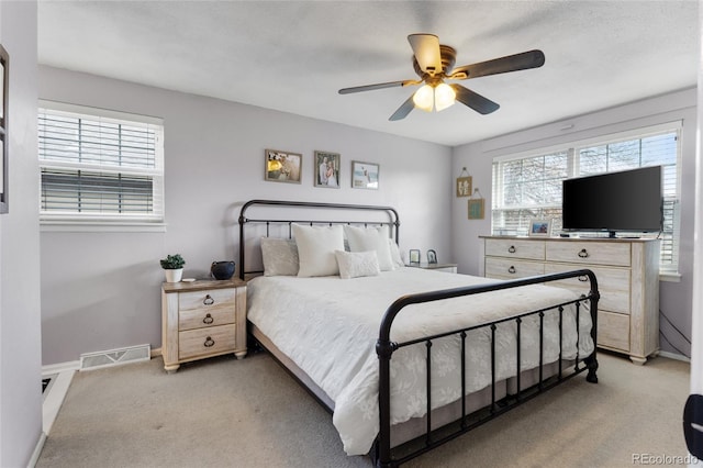 bedroom with light colored carpet, visible vents, baseboards, and multiple windows