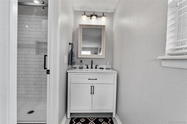 bathroom with baseboards, a shower stall, and vanity