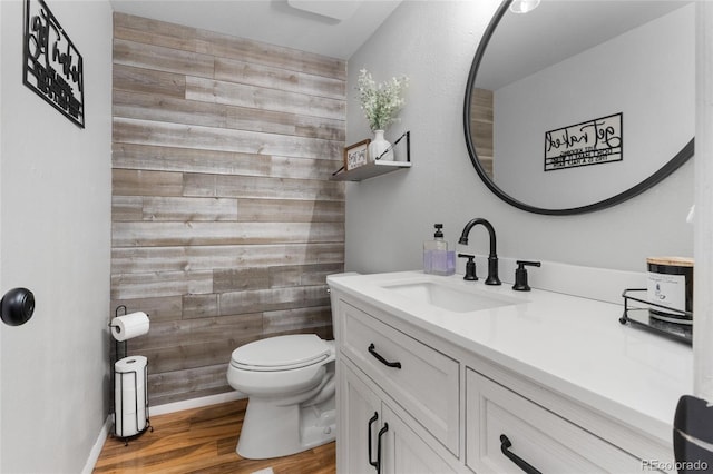 bathroom featuring wood finished floors, vanity, toilet, and wooden walls