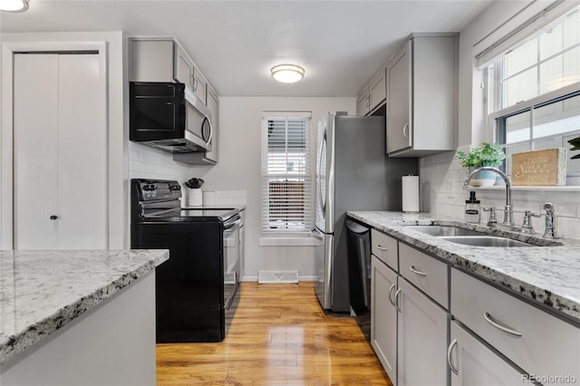 kitchen with black appliances, plenty of natural light, gray cabinets, and a sink