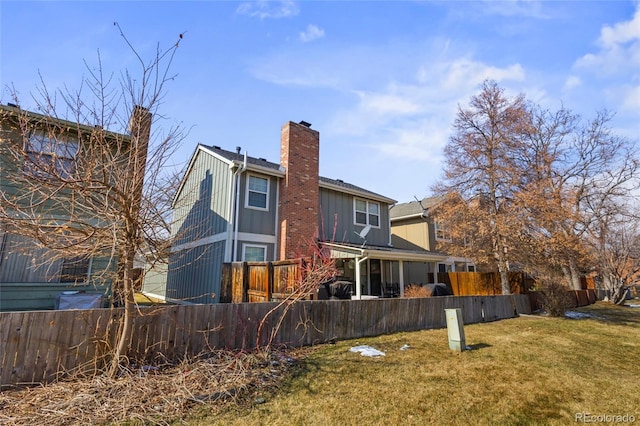 rear view of property featuring board and batten siding, a chimney, fence, and a lawn