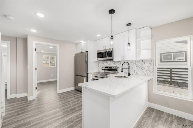 kitchen with pendant lighting, sink, kitchen peninsula, white cabinetry, and stainless steel appliances