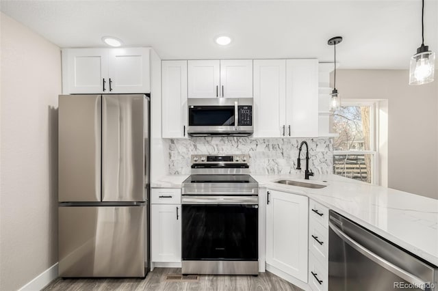 kitchen with decorative light fixtures, white cabinetry, sink, and appliances with stainless steel finishes