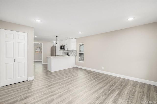 unfurnished living room with sink and light hardwood / wood-style floors