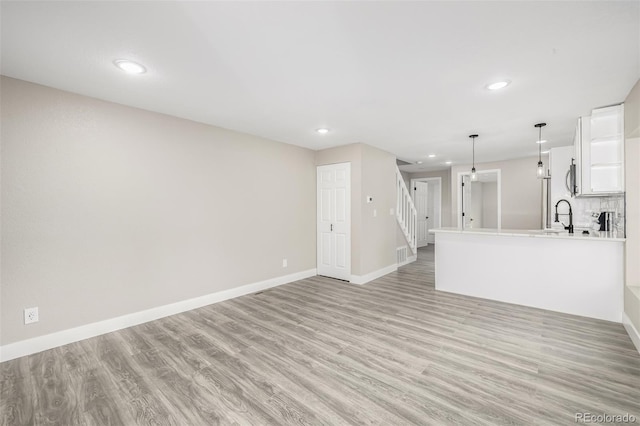 unfurnished living room with sink and light wood-type flooring