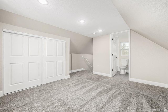 bonus room with a textured ceiling, light carpet, and lofted ceiling