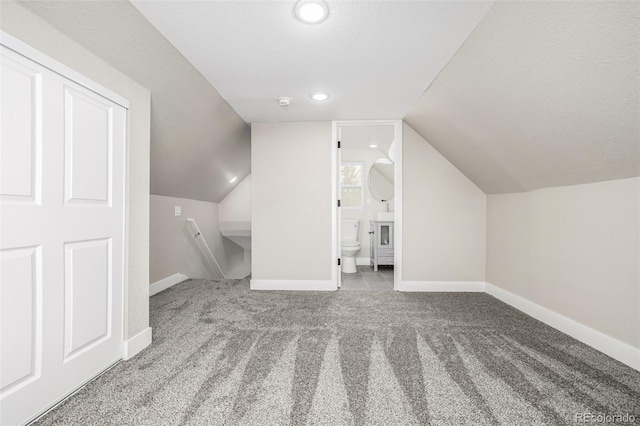 bonus room with a textured ceiling, light carpet, and lofted ceiling