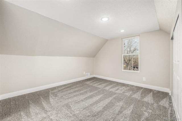 bonus room featuring a textured ceiling, carpet floors, and vaulted ceiling