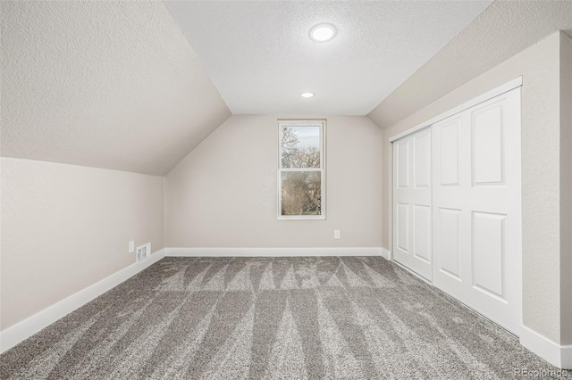 additional living space featuring carpet, a textured ceiling, and lofted ceiling