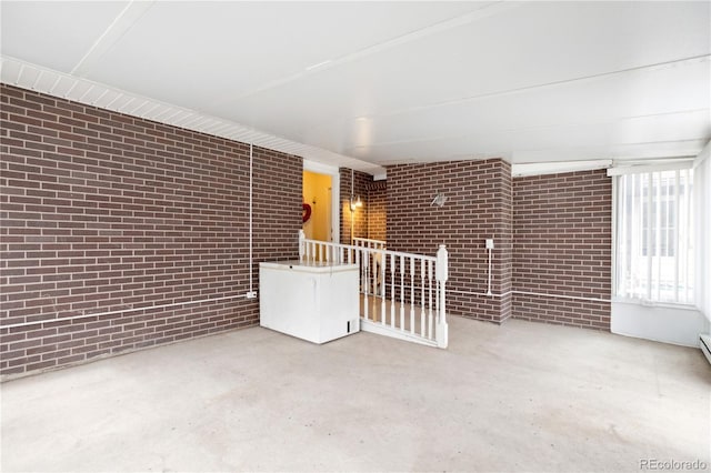 unfurnished room featuring brick wall and concrete floors