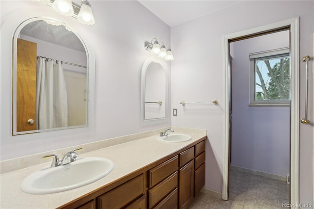 bathroom with baseboards and double vanity