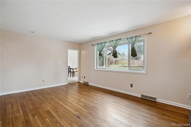 spare room with hardwood / wood-style floors and baseboards