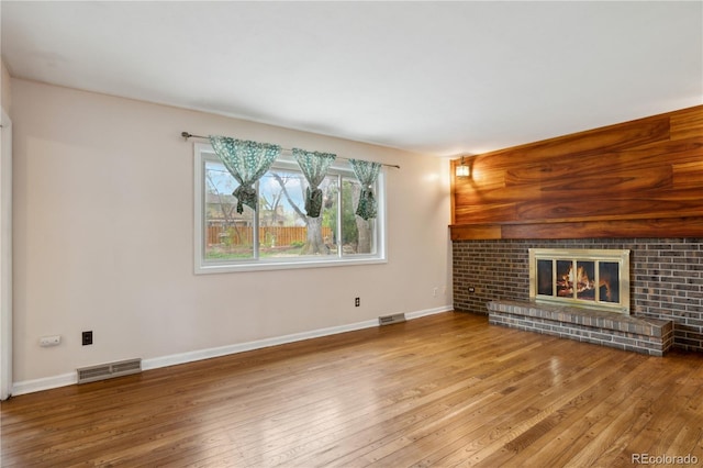 unfurnished living room with hardwood / wood-style flooring, a fireplace, and baseboards