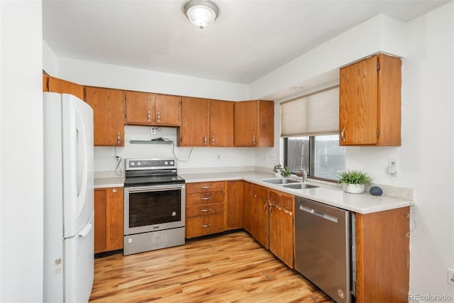 kitchen with stainless steel appliances, sink, and light hardwood / wood-style floors