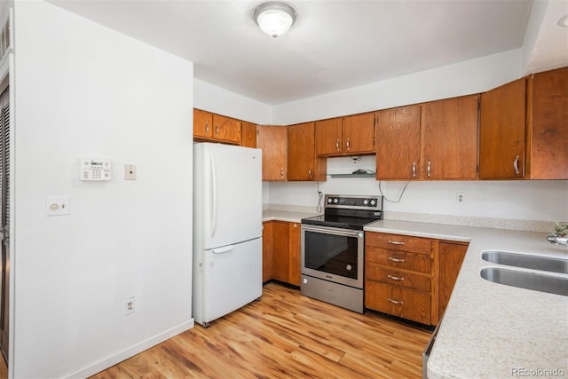 kitchen with white fridge, stainless steel electric range oven, light hardwood / wood-style floors, and sink