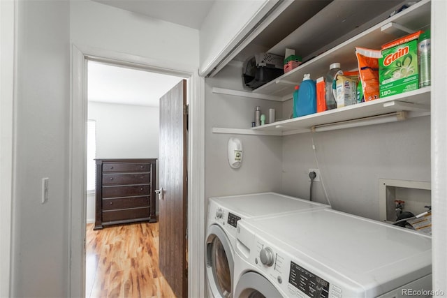 clothes washing area with light hardwood / wood-style floors and washer and clothes dryer