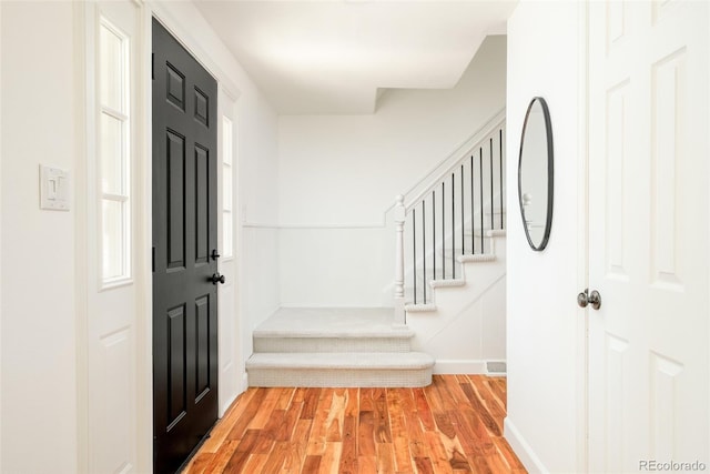 entryway with light wood-style floors, stairs, and baseboards