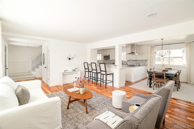 living room with light wood-type flooring, baseboards, and stairs