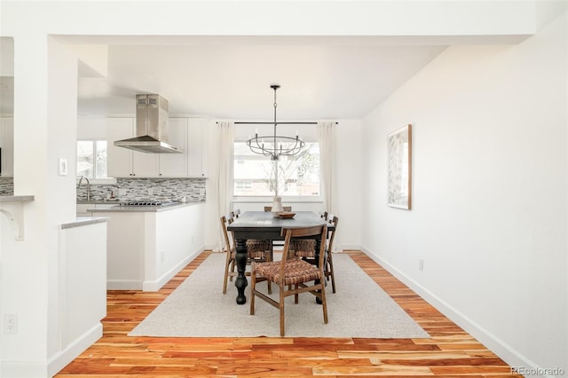 dining area featuring light wood-type flooring, plenty of natural light, and a notable chandelier