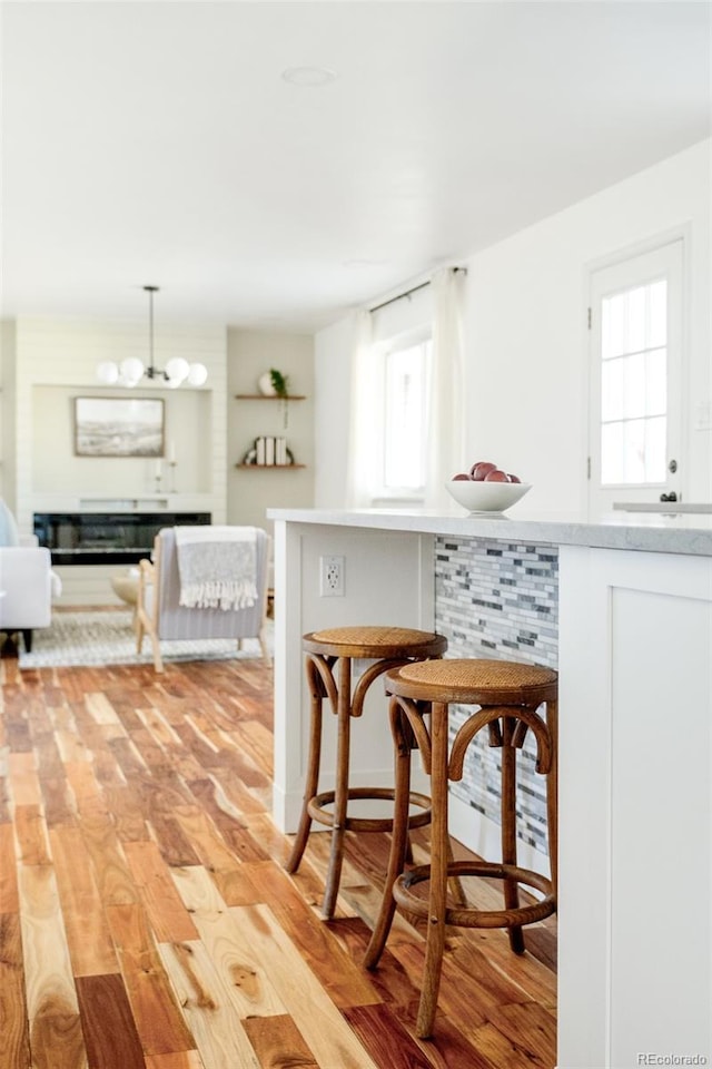 kitchen featuring a chandelier, a kitchen breakfast bar, light countertops, light wood-type flooring, and decorative light fixtures