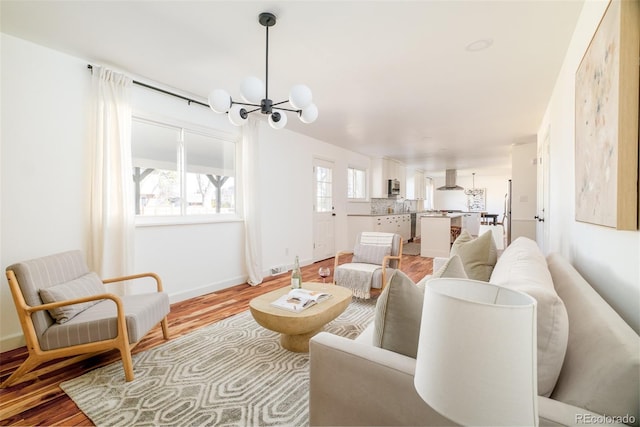 living area with a notable chandelier, light wood-style flooring, and baseboards