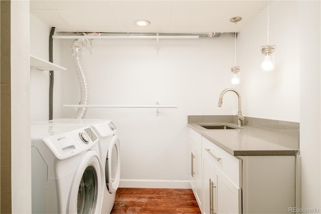 laundry room featuring wood finished floors, separate washer and dryer, a sink, and baseboards